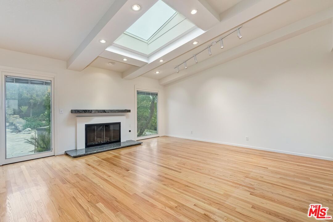 18409 Wakecrest Drive Malibu, CA 90265 - Photo 13 of 32 an empty room with wooden floor fireplace and windows