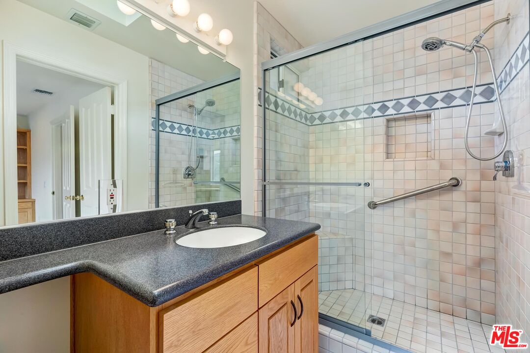 18409 Wakecrest Drive Malibu, CA 90265 - Photo 25 of 32 a bathroom with a sink vanity granite shower and a mirror