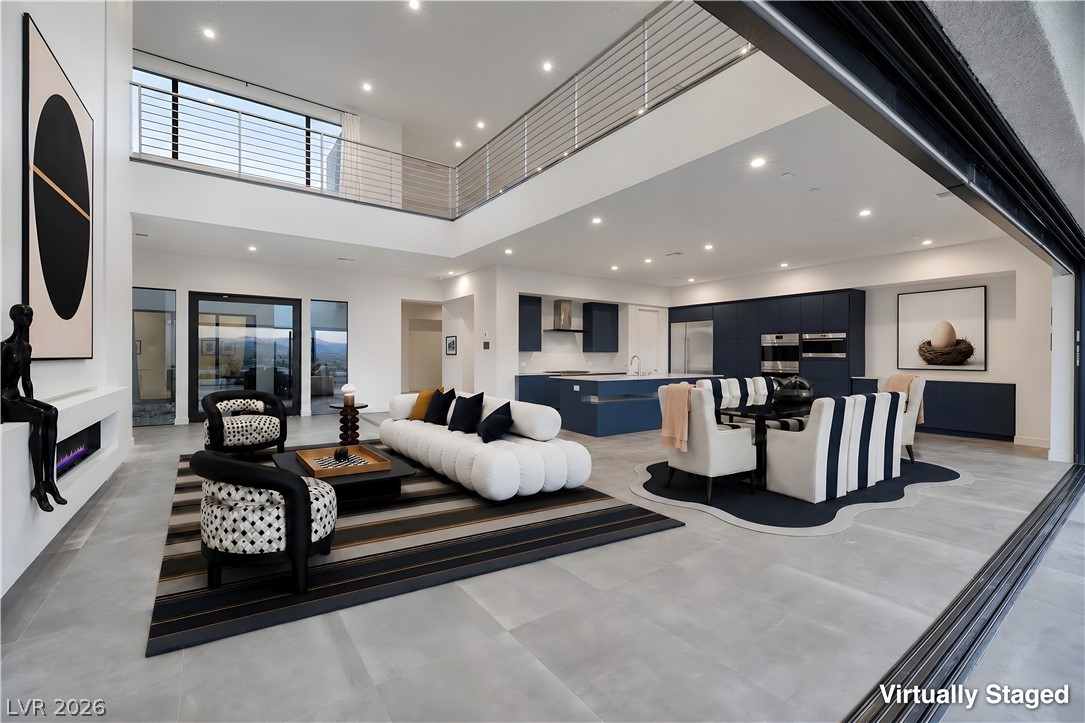 25 Falling Ridge Lane Henderson, NV 89011 - Photo 11 of 48 An open-concept living space with a contemporary fireplace and soaring ceilings, featuring an upper-level walkway and seamless outdoor access.