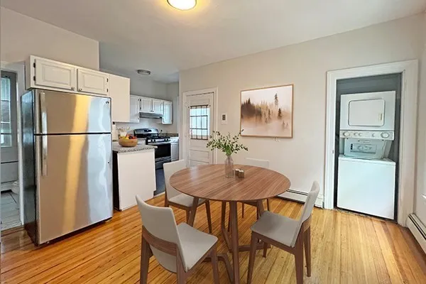 a kitchen with stainless steel appliances a refrigerator a stove a dining table and chairs