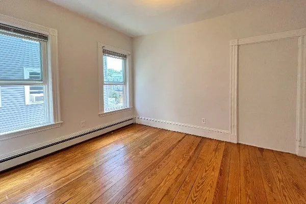 a view of an empty room with wooden floor and a window