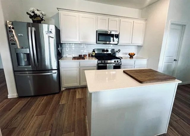 a kitchen with a refrigerator a stove top oven a sink and cabinets