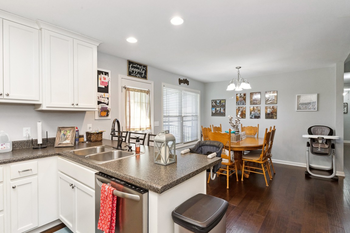 957 Jimtown Road Lafayette, TN 37083 - Photo 9 of 25 a kitchen with stainless steel appliances granite countertop a sink a stove a dining table and chairs with wooden floor
