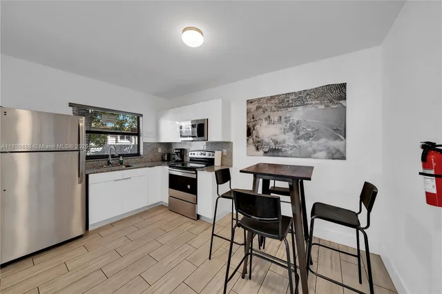 a kitchen with stainless steel appliances kitchen island a table chairs refrigerator and sink