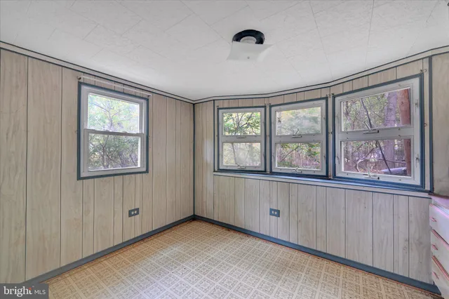 a view of an empty room with a window and a kitchen