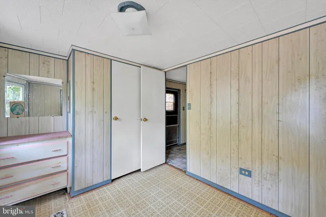 a view of an empty room with closet and entryway