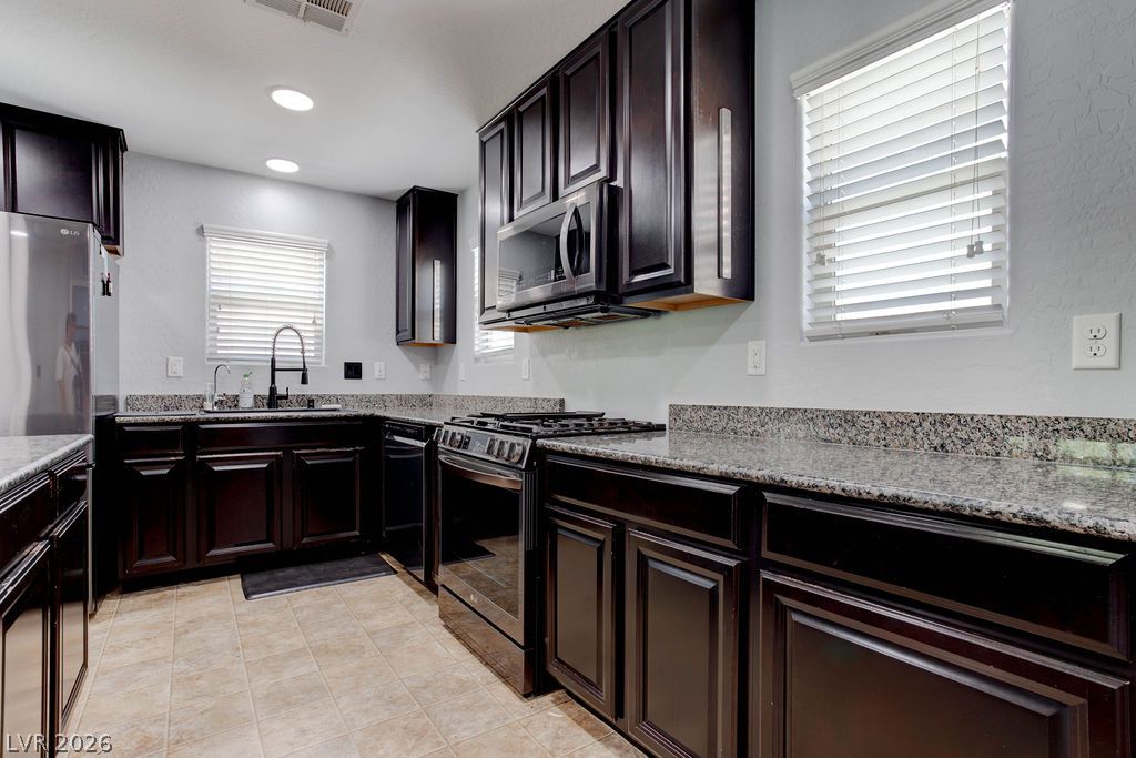 7724 Vibrant Thread Court Las Vegas, NV 89149 - Photo 13 of 43 A well-appointed kitchen features dark cabinetry, sparkling granite counters, and modern appliances.
