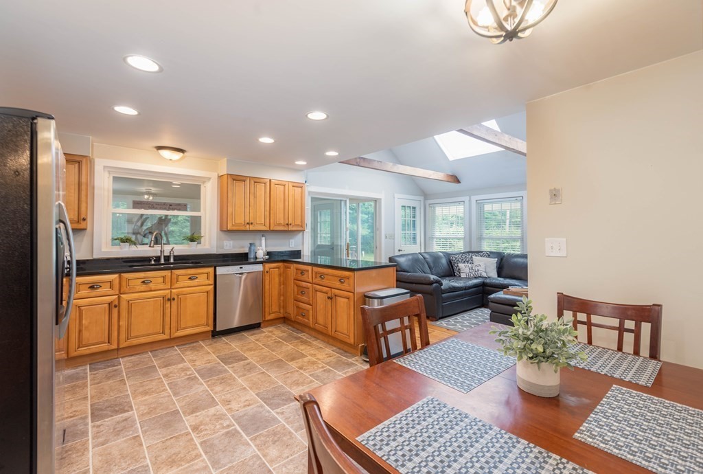17 Norwood Road Salem, NH 03079 - Photo 3 of 24 a kitchen with stainless steel appliances granite countertop a refrigerator a sink a stove a dining table and chairs with wooden floor