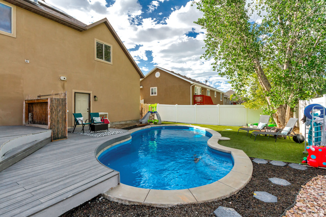 1585 South 910 West Payson, UT 84651 - Photo 23 of 32 Backyard oasis featuring a freeform swimming pool, extensive composite decking, artificial turf, and mature shade trees