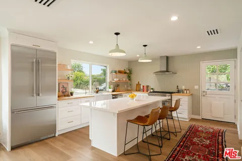 a kitchen with a sink a refrigerator and chairs
