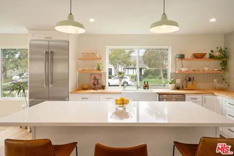 a large kitchen with kitchen island a large window cabinets and stainless steel appliances