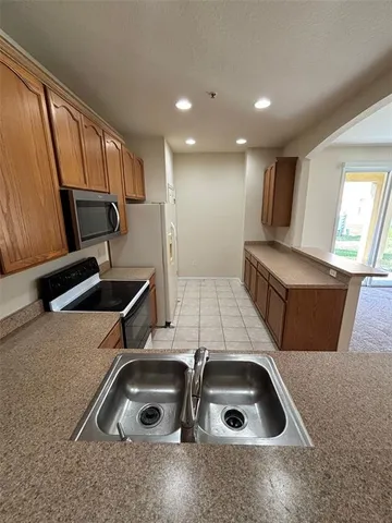 a kitchen with granite countertop a sink a counter top space and cabinets