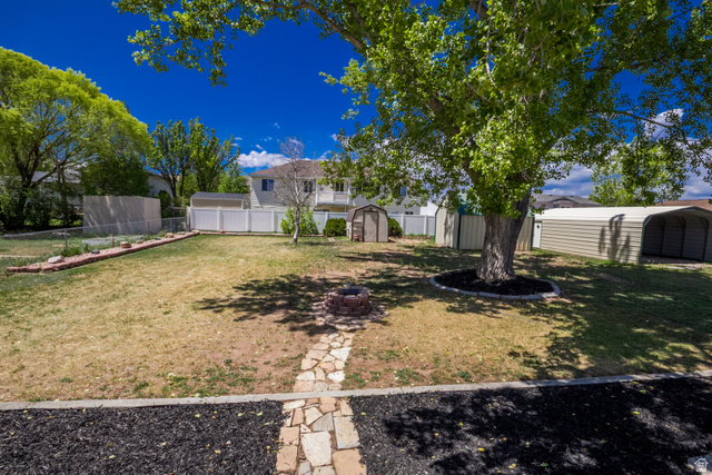 634 South 2100th Street West Vernal, UT 84078 - Photo 50 of 71 Expansive backyard featuring a mature tree with mulched base, a stone fire pit, and a flagstone pathway