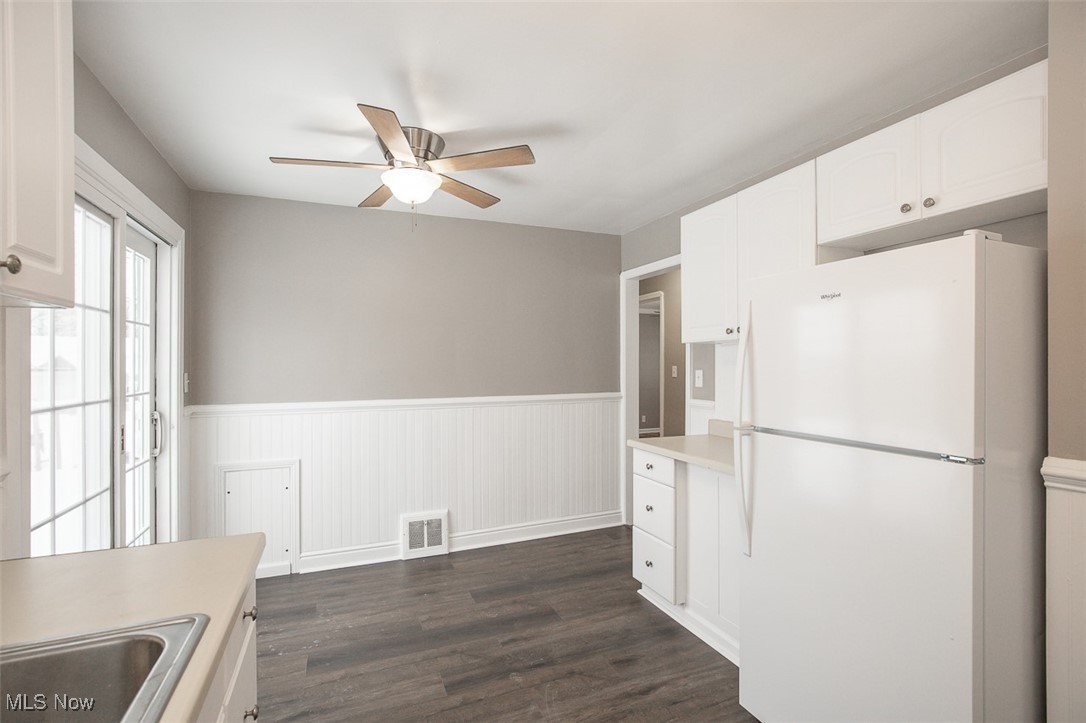 12328 Granger Road Cleveland, OH 44125 - Photo 19 of 37 Kitchen featuring freestanding refrigerator, a wainscoted wall, light countertops, dark wood-style floors, and white cabinets