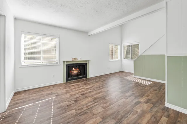 an empty room with windows fireplace and wooden floor