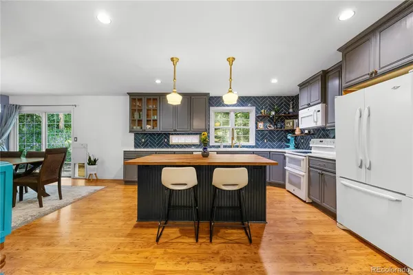 a kitchen with stainless steel appliances granite countertop a sink a stove a refrigerator cabinets and chairs