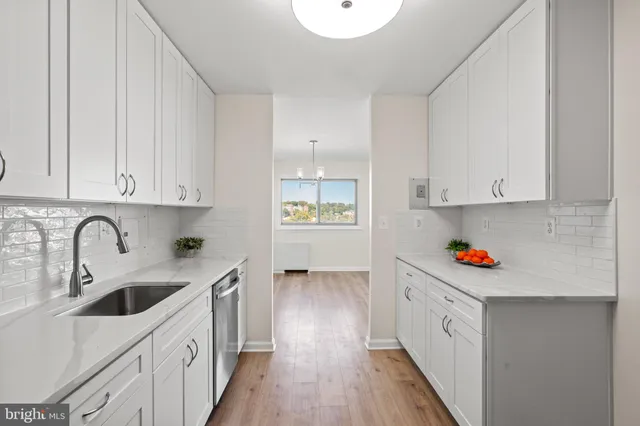 a kitchen with stainless steel appliances a sink dishwasher and cabinets with wooden floor