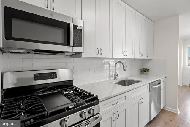 a kitchen with stainless steel appliances a sink stove and microwave