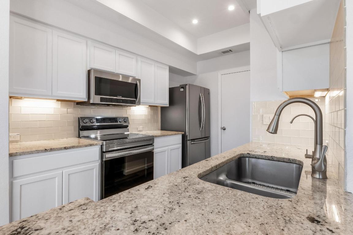 4711 Spicewood Springs Road, Unit 166 Austin, TX 78759 - Photo 9 of 25 a kitchen with stainless steel appliances granite countertop a sink a stove a refrigerator cabinets and a counter top space