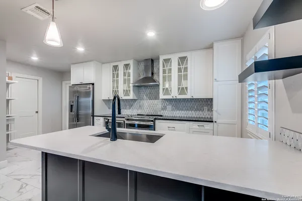 a kitchen with stainless steel appliances a sink a stove a refrigerator a center island and cabinets