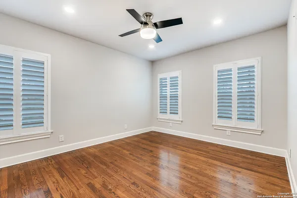 an empty room with wooden floor and windows