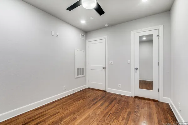 an empty room with wooden floor and windows