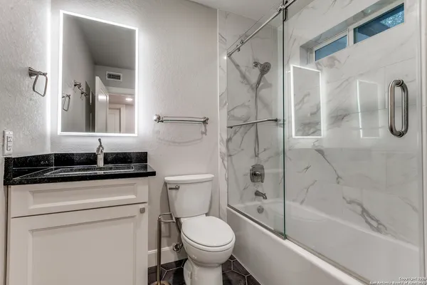 a bathroom with a granite countertop sink toilet and shower