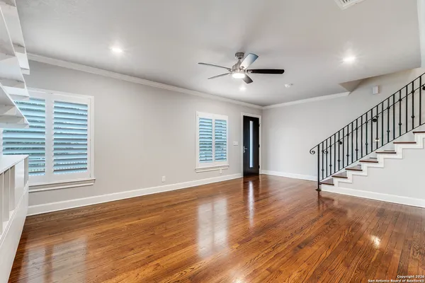 a view of an empty room with wooden floor and a window