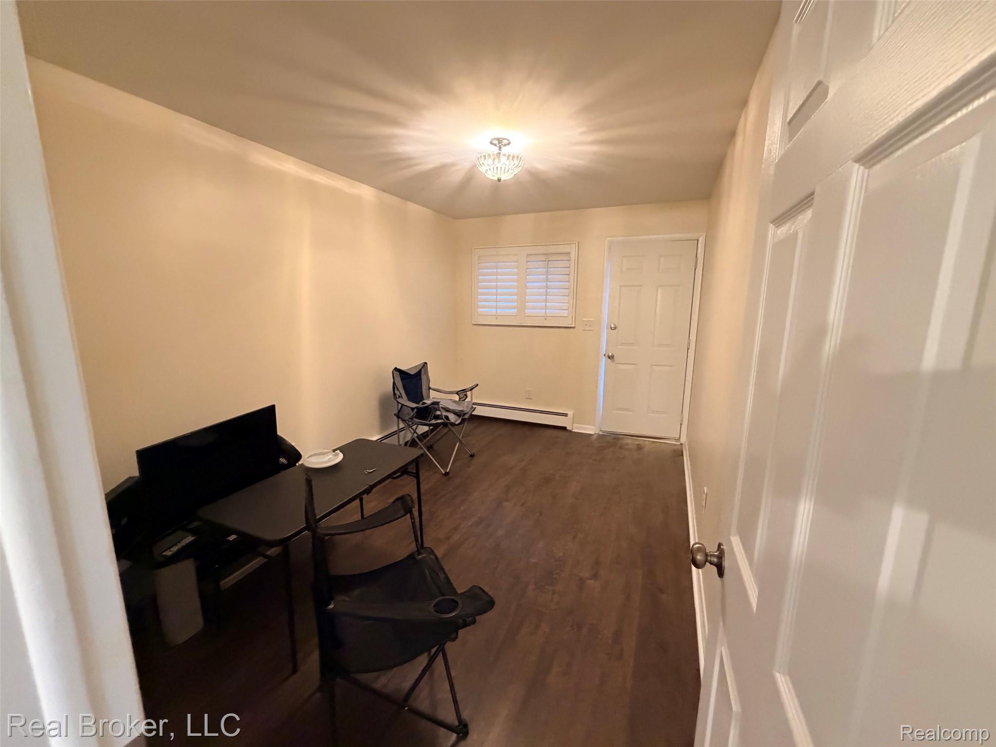 22444 Kelly Road, Unit 11 Eastpointe, MI 48021 - Photo 15 of 18 Wood-finish flooring, white paneled door, window with white plantation shutters, ceiling-mounted light fixture, and baseboard heating