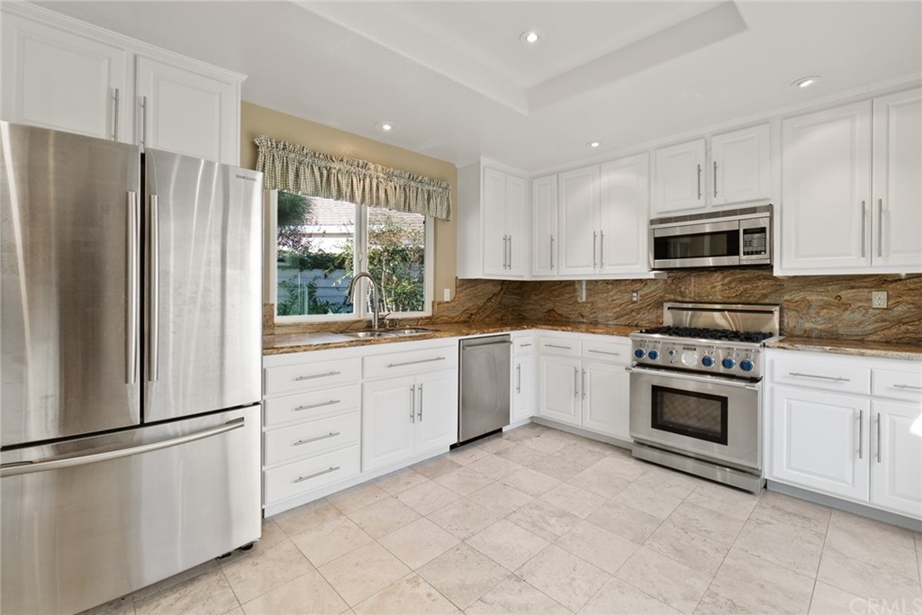 5 Elderwood, Unit 19 Irvine, CA 92614 - Photo 2 of 39 a kitchen with granite countertop white cabinets and stainless steel appliances