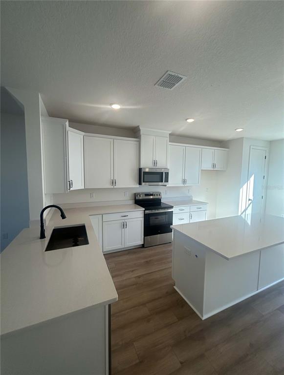 15274 Groveside Road Winter Garden, FL 34787 - Photo 3 of 4 a kitchen with a sink a stove a refrigerator and cabinets