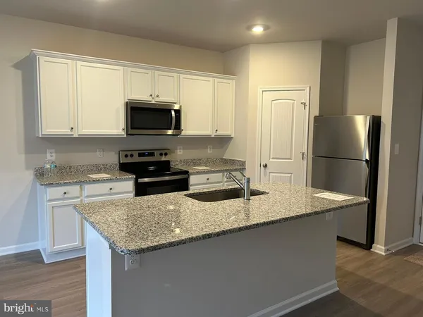 a kitchen with granite countertop a refrigerator and a stove top oven