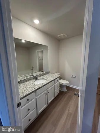 a bathroom with a granite countertop sink a toilet a mirror and vanity