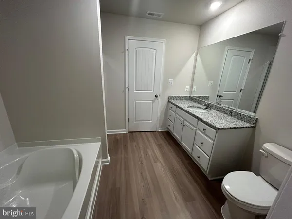 a bathroom with a granite countertop toilet sink and mirror