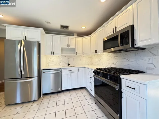 a kitchen with stainless steel appliances granite countertop a stove a refrigerator and a microwave