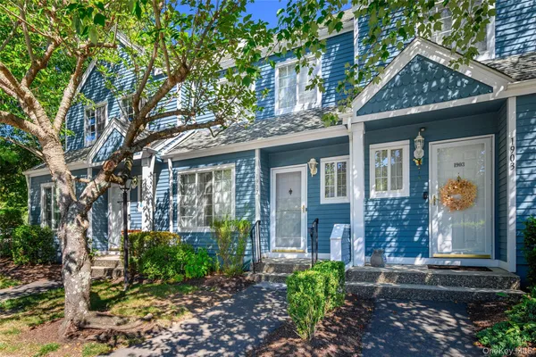 a view of a brick house with a large windows plants and large trees