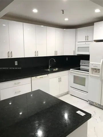 a kitchen with granite countertop a cabinets and white stainless steel appliances