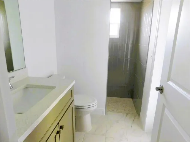 a bathroom with a granite countertop sink toilet and shower