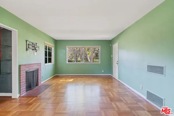a view of an empty room with a fireplace and a window