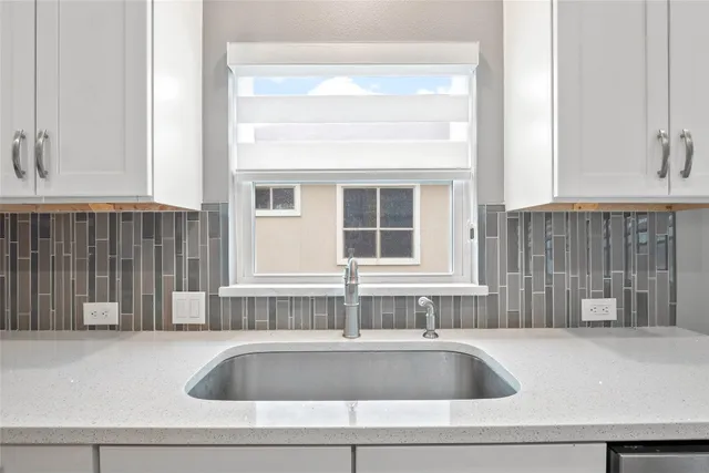 a large kitchen with kitchen island a sink dishwasher a stove and white cabinets with wooden floor