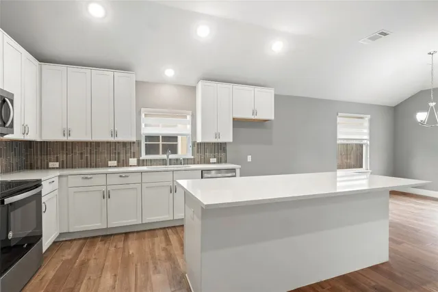 a large kitchen with stainless steel appliances kitchen island a stove a sink a refrigerator and cabinets