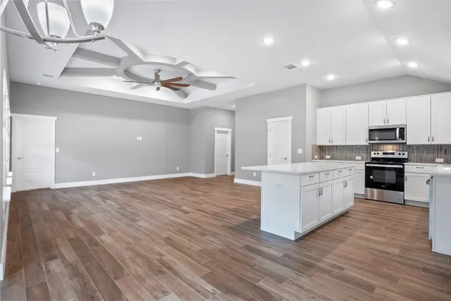 a large kitchen with stainless steel appliances granite countertop a stove top oven a sink with wooden floors