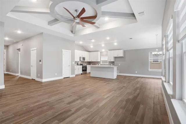 a view of a livingroom with a ceiling fan wooden floor and a ceiling fan