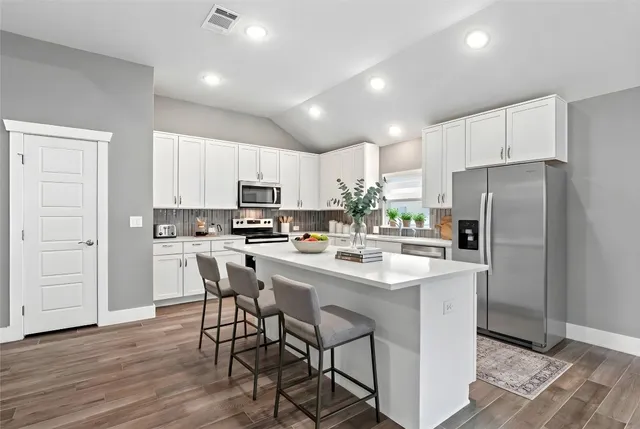 a kitchen with stainless steel appliances a table chairs refrigerator and a sink