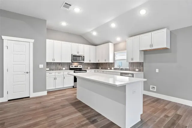 a kitchen with white cabinets and sink
