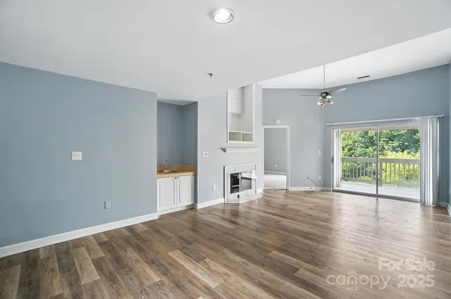 an empty room with fireplace wooden floor and windows