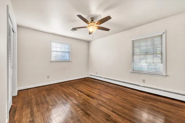 a view of empty room with wooden floor and fan