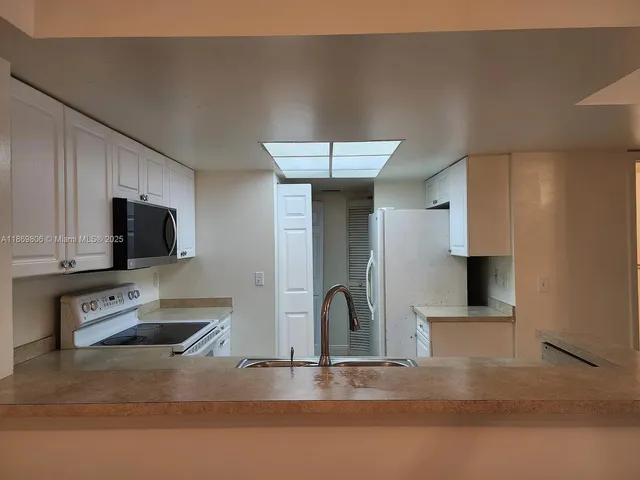 a kitchen with stainless steel appliances kitchen island sink refrigerator and stove