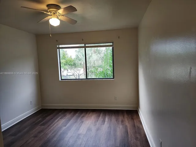 an empty room with wooden floor chandelier fan and windows
