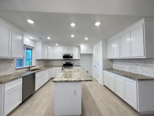 a kitchen with granite countertop sink stove and cabinets
